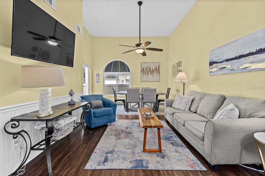A living and dining area features vaulted ceilings, a gray sofa, and a blue armchair — 8600 RIDGEWOOD AVENUE UNIT 1311, CAPE CANAVERAL, FL