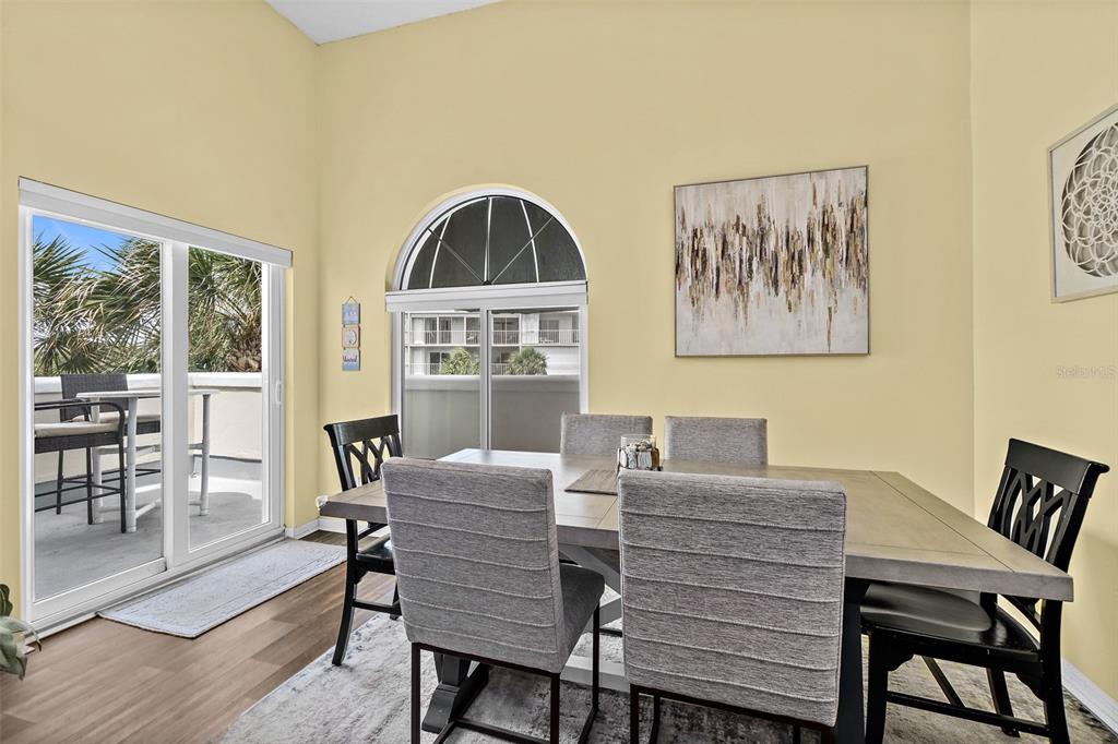 A dining room with a wooden table, gray chairs, and a large arched window — 8600 RIDGEWOOD AVENUE UNIT 1311, CAPE CANAVERAL, FL