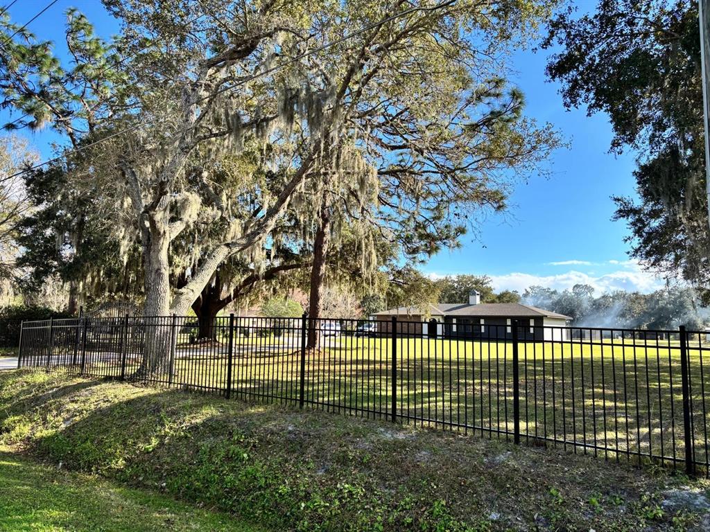 A black metal fence encloses a grassy yard in front of a single-story house — 1800 GRANADA BOULEVARD, KISSIMMEE, FL