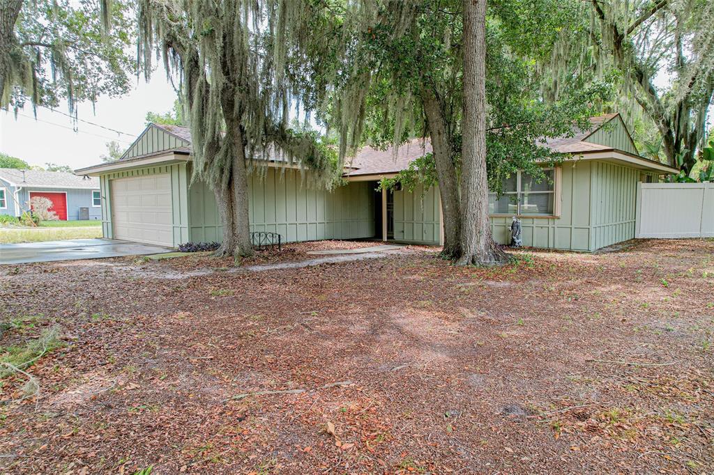 A single-story house with green vertical siding, a two-car garage, and large oak trees — 4604 CRYSTAL BEACH ROAD, WINTER HAVEN, FL