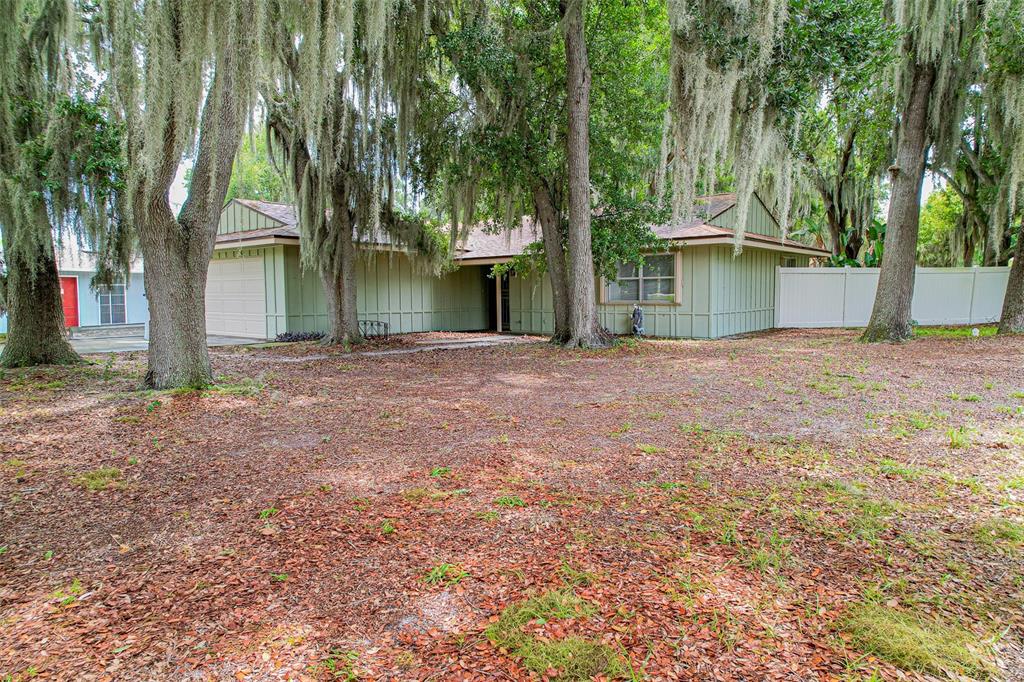 A single-story house with light green vertical siding sits behind large trees with Spanish moss — 4604 CRYSTAL BEACH ROAD, WINTER HAVEN, FL