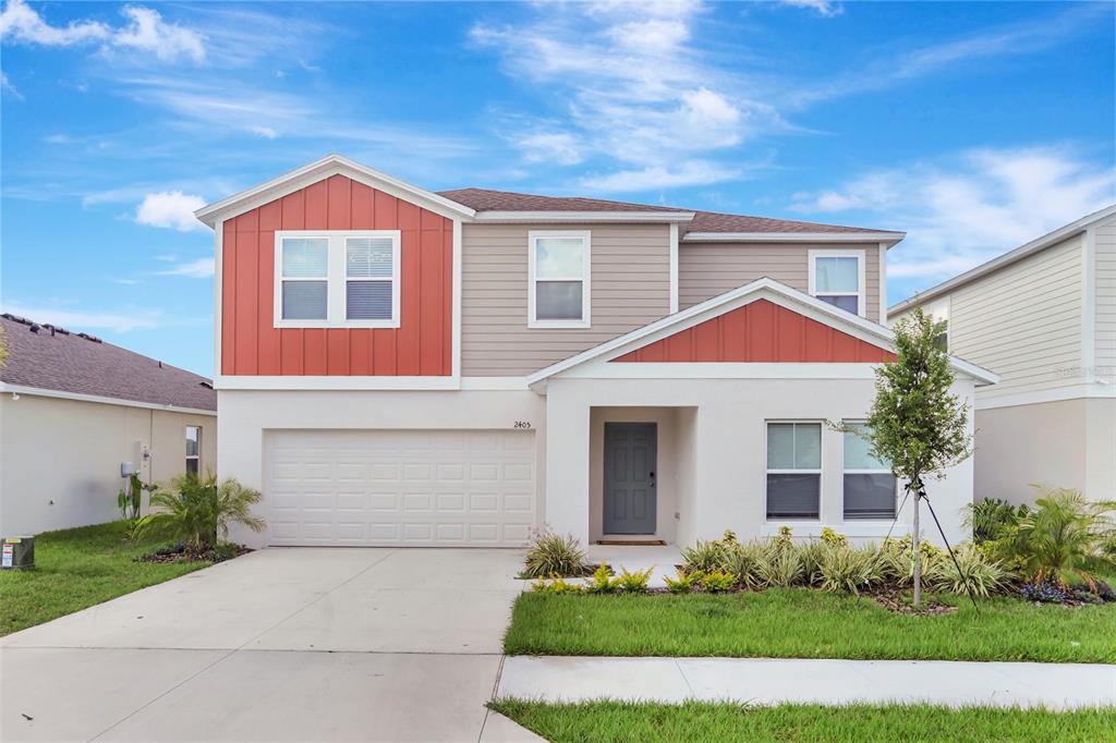 A two-story house features a white stucco lower level, tan siding, and red vertical accents — 2405 OAKWOOD LANE, DAVENPORT, FL