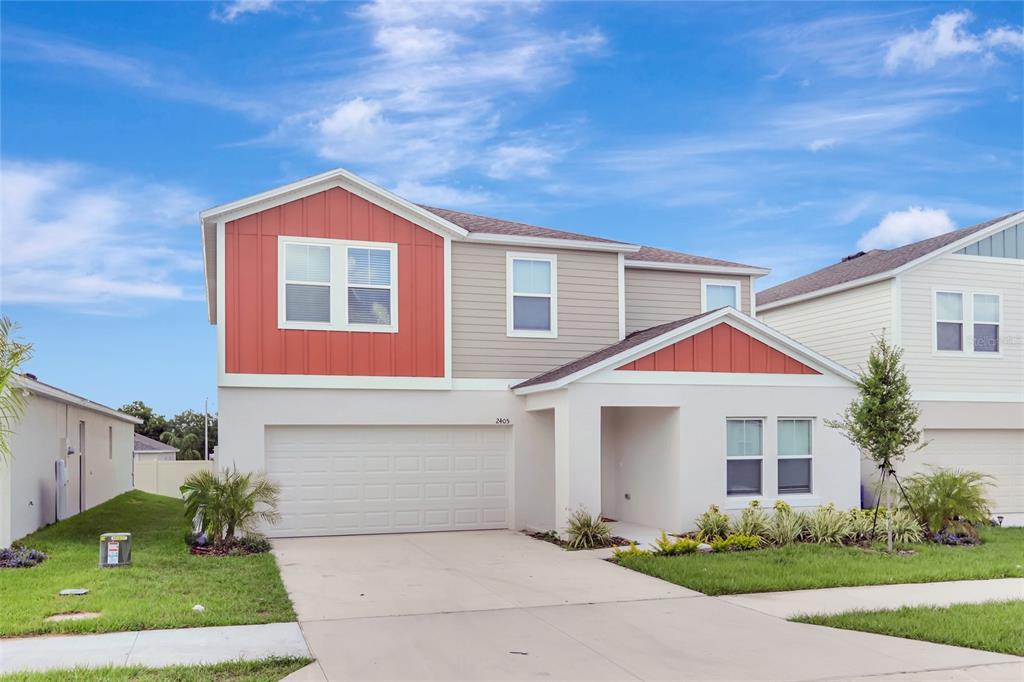 A two-story suburban house features a white stucco lower level, red and tan siding, and a garage — 2405 OAKWOOD LANE, DAVENPORT, FL