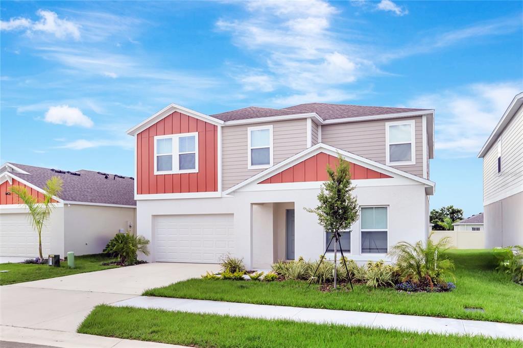A two-story suburban house with a white stucco facade, red accents, and a two-car garage — 2405 OAKWOOD LANE, DAVENPORT, FL