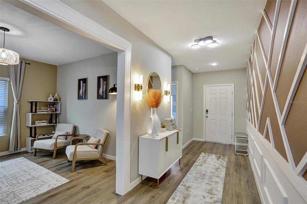 A bright entryway leads into a living area with wood floors and decorative wall molding — 2405 OAKWOOD LANE, DAVENPORT, FL