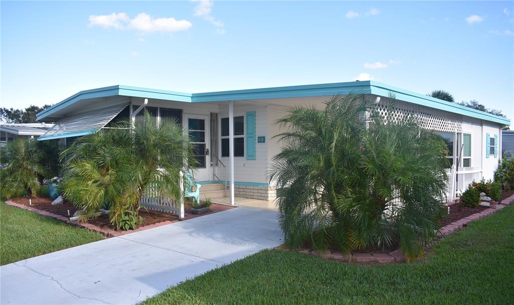 A single-story mobile home with a turquoise roof, white siding, and palm trees in front — 410 HAWTHORNE BOULEVARD, LEESBURG, FL