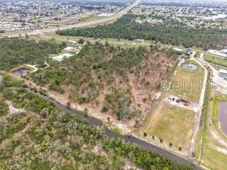 An aerial view shows a large, undeveloped plot of land bordered by trees and roads — 24540 YACHT CLUB BOULEVARD, PUNTA GORDA, FL