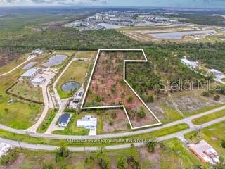 An aerial view shows a vacant, wooded lot outlined in white within a rural landscape — 24540 YACHT CLUB BOULEVARD, PUNTA GORDA, FL