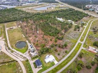 An aerial view shows a vacant, wooded lot marked by an arrow near residential streets — 24540 YACHT CLUB BOULEVARD, PUNTA GORDA, FL