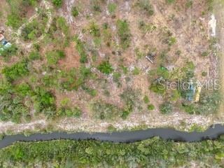 An aerial view shows a wooded lot bordering a narrow canal — 24540 YACHT CLUB BOULEVARD, PUNTA GORDA, FL