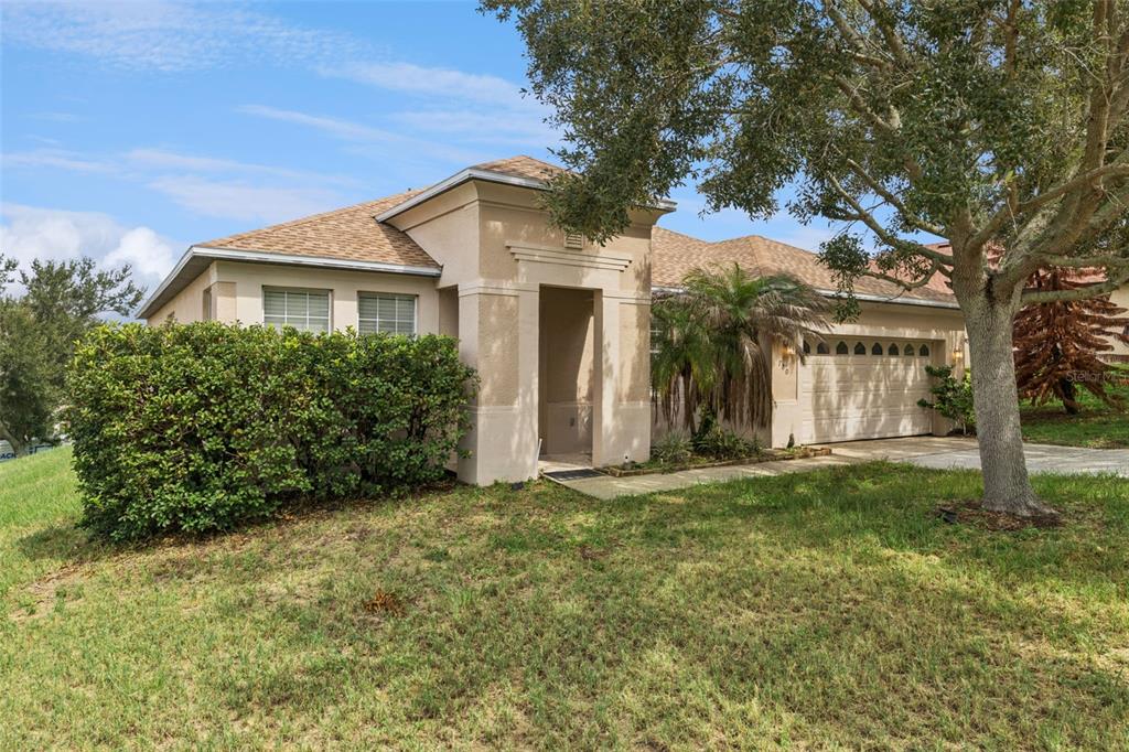 A one-story beige stucco house with a two-car garage and a large front hedge — 780 LAKEVIEW POINTE DRIVE, CLERMONT, FL