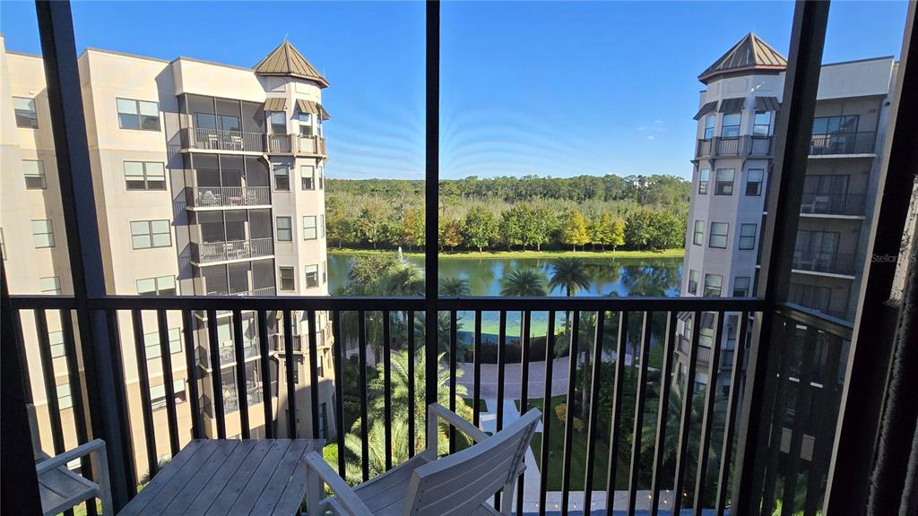 A view from a screened balcony overlooking a lake between two multi-story apartment buildings — 14501 GROVE RESORT AVENUE UNIT 1603, WINTER GARDEN, FL