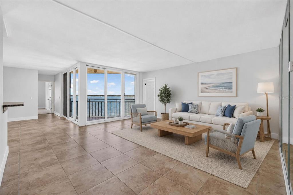 A living room with tile floors, a white sofa, two armchairs, and a waterfront balcony — 5541 PUERTA DEL SOL BOULEVARD S UNIT 412, ST PETERSBURG, FL