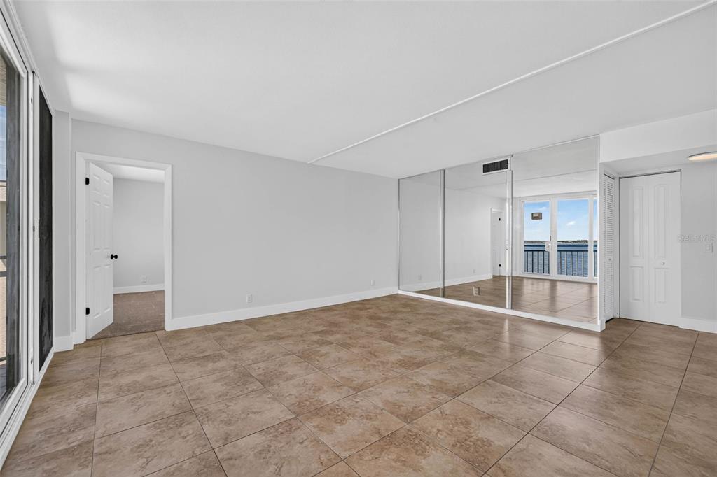 An empty room with tiled floors, mirrored walls, and a doorway leading to a balcony — 5541 PUERTA DEL SOL BOULEVARD S UNIT 412, ST PETERSBURG, FL