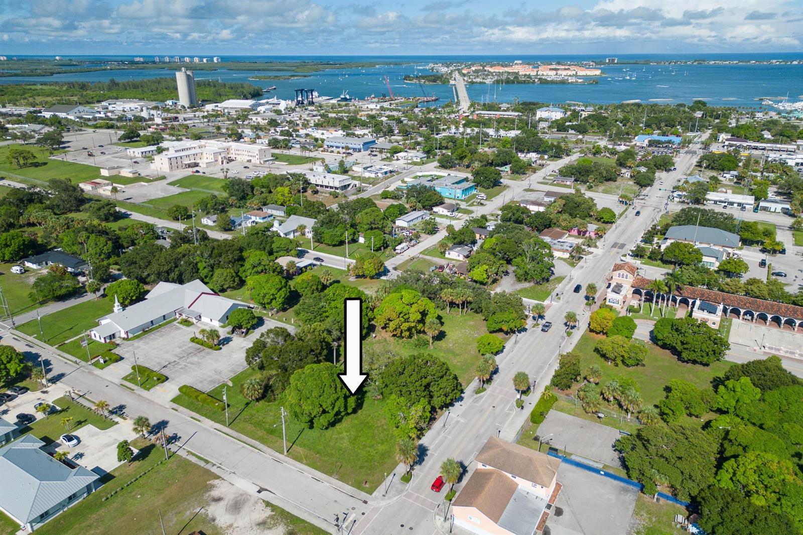 An aerial view shows a vacant, tree-lined lot marked by a white arrow in a neighborhood — N 9th Street, Fort Pierce FL 34950, FORT PIERCE, FL