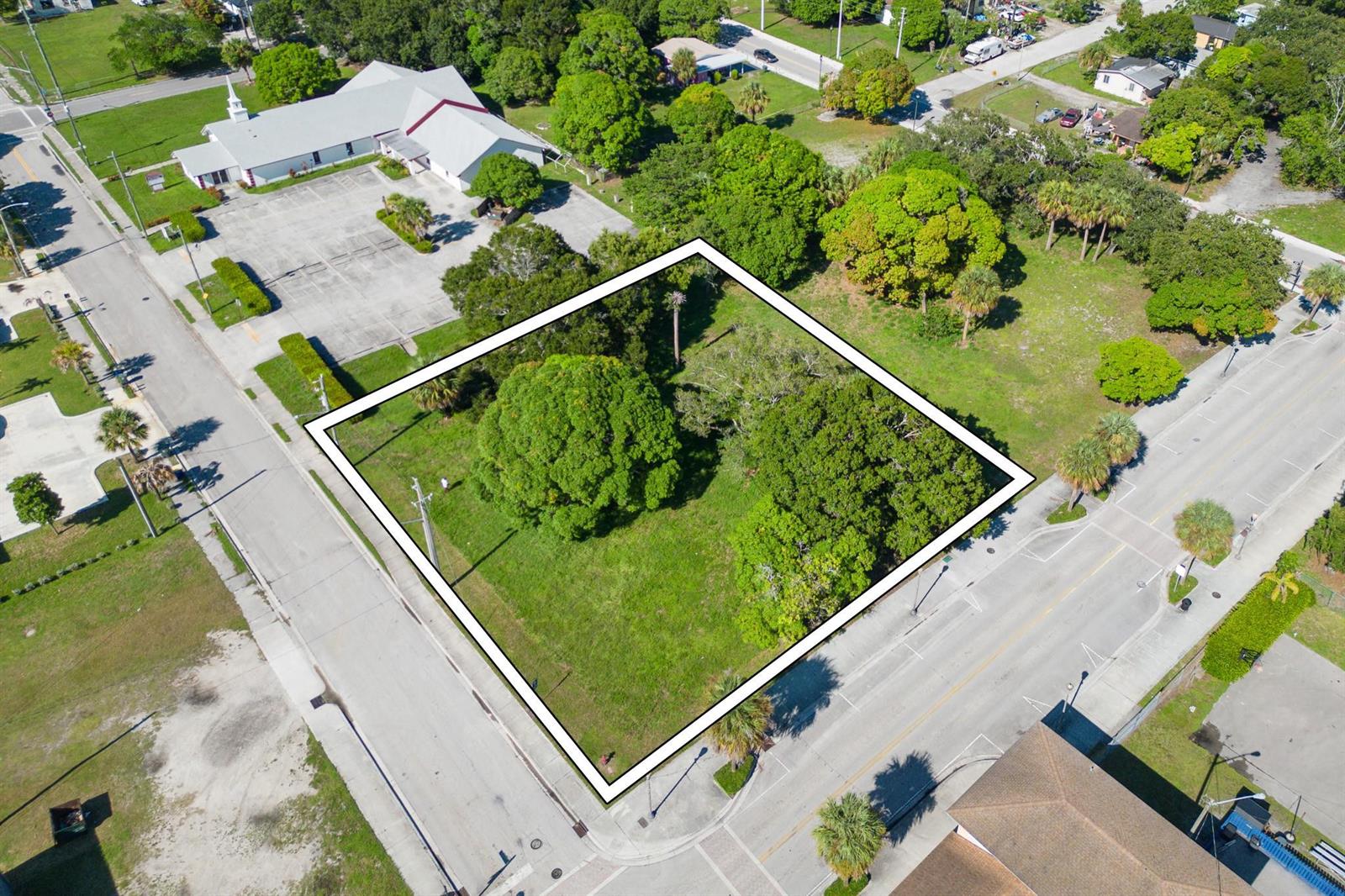 An aerial view shows a vacant, grass-covered rectangular lot outlined in white near a road — N 9th Street, Fort Pierce FL 34950, FORT PIERCE, FL