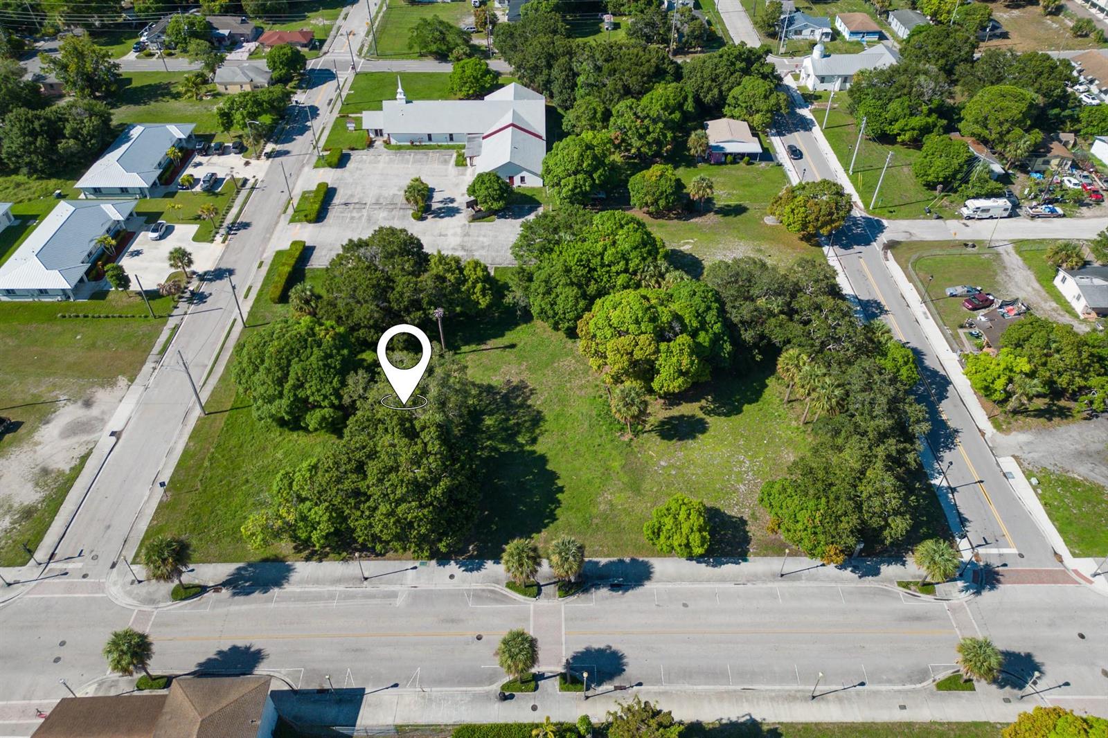 An aerial view shows a vacant, tree-filled lot bordered by paved streets and nearby buildings — N 9th Street, Fort Pierce FL 34950, FORT PIERCE, FL