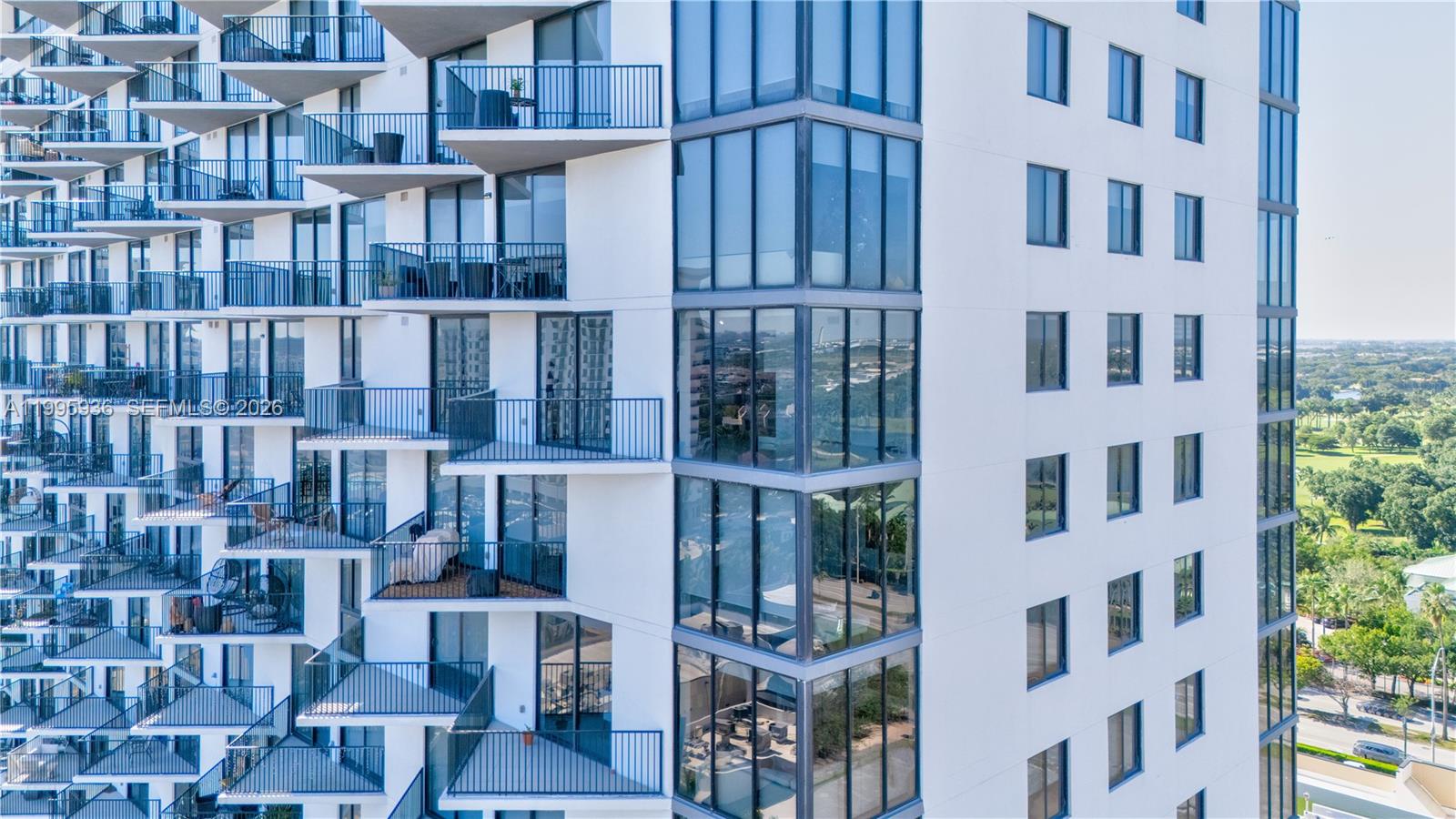 An exterior view of a modern high-rise building featuring stacked balconies and floor-to-ceiling windows — 5300 NW 85th St # 1511, Doral FL 33166, DORAL, FL