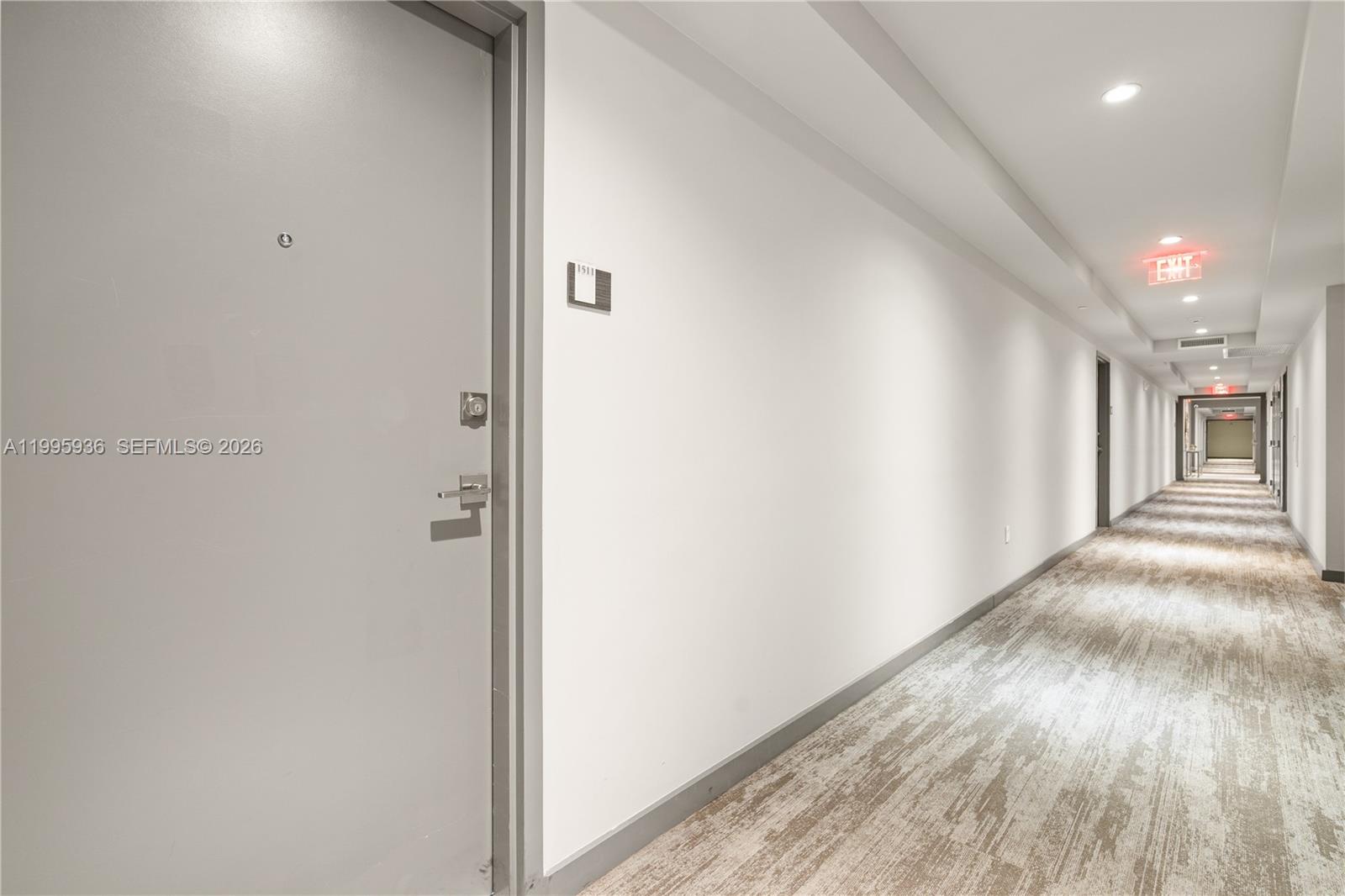 A long, brightly lit apartment hallway features gray doors, white walls, and patterned carpeting — 5300 NW 85th St # 1511, Doral FL 33166, DORAL, FL