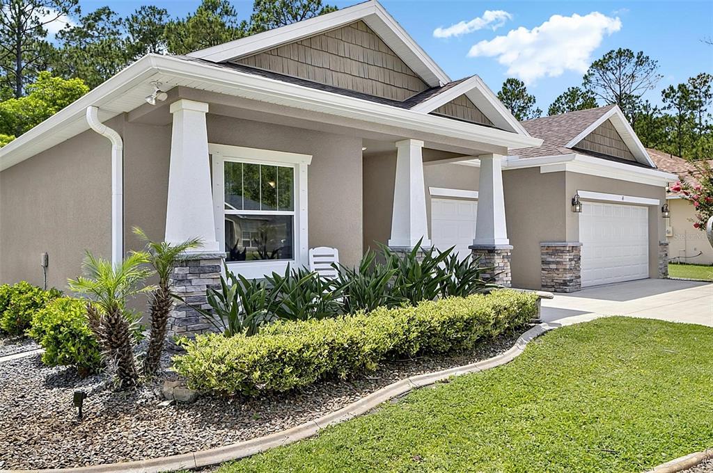 A single-story house exterior features a gray stucco facade, stone accents, and a front porch — 45 ZONAL GERANIUM TRAIL, PALM COAST, FL