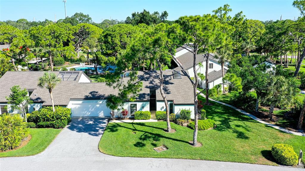An aerial view of a single-story residential building with a driveway and surrounding trees — 4391 WOODMANS CHART UNIT 155, SARASOTA, FL