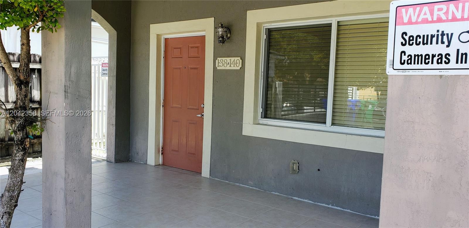 A covered porch features a red door, a window with blinds, and a security sign — 138 NW 31st St # 138, Miami FL 33127, MIAMI, FL