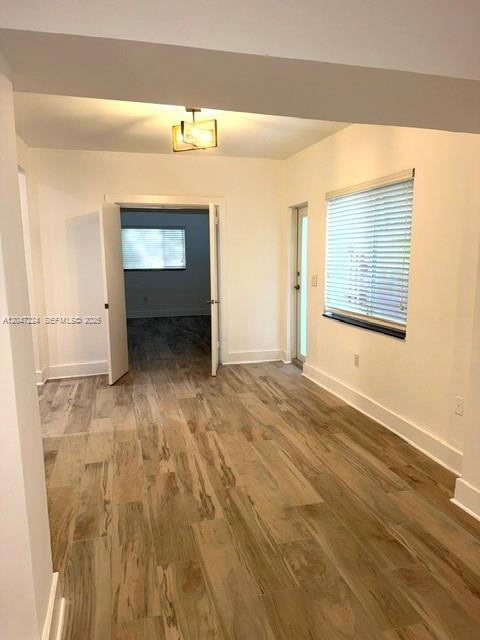 A room with wood-look tile flooring, a doorway to another room, and a window with blinds — 1553 Jefferson Ave # 1, Miami Beach FL 33139, MIAMI BEACH, FL