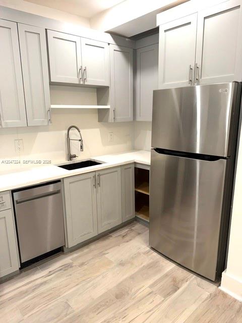 A kitchen features light gray cabinets, stainless steel appliances, and wood-look flooring — 1553 Jefferson Ave # 1, Miami Beach FL 33139, MIAMI BEACH, FL