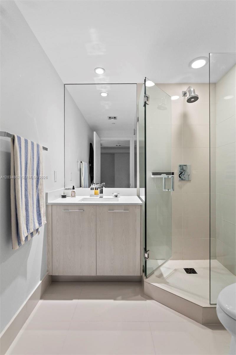 A modern bathroom features a light wood vanity, a large mirror, and a glass shower — 55 SW 9th St # 1105, Miami FL 33130, MIAMI, FL