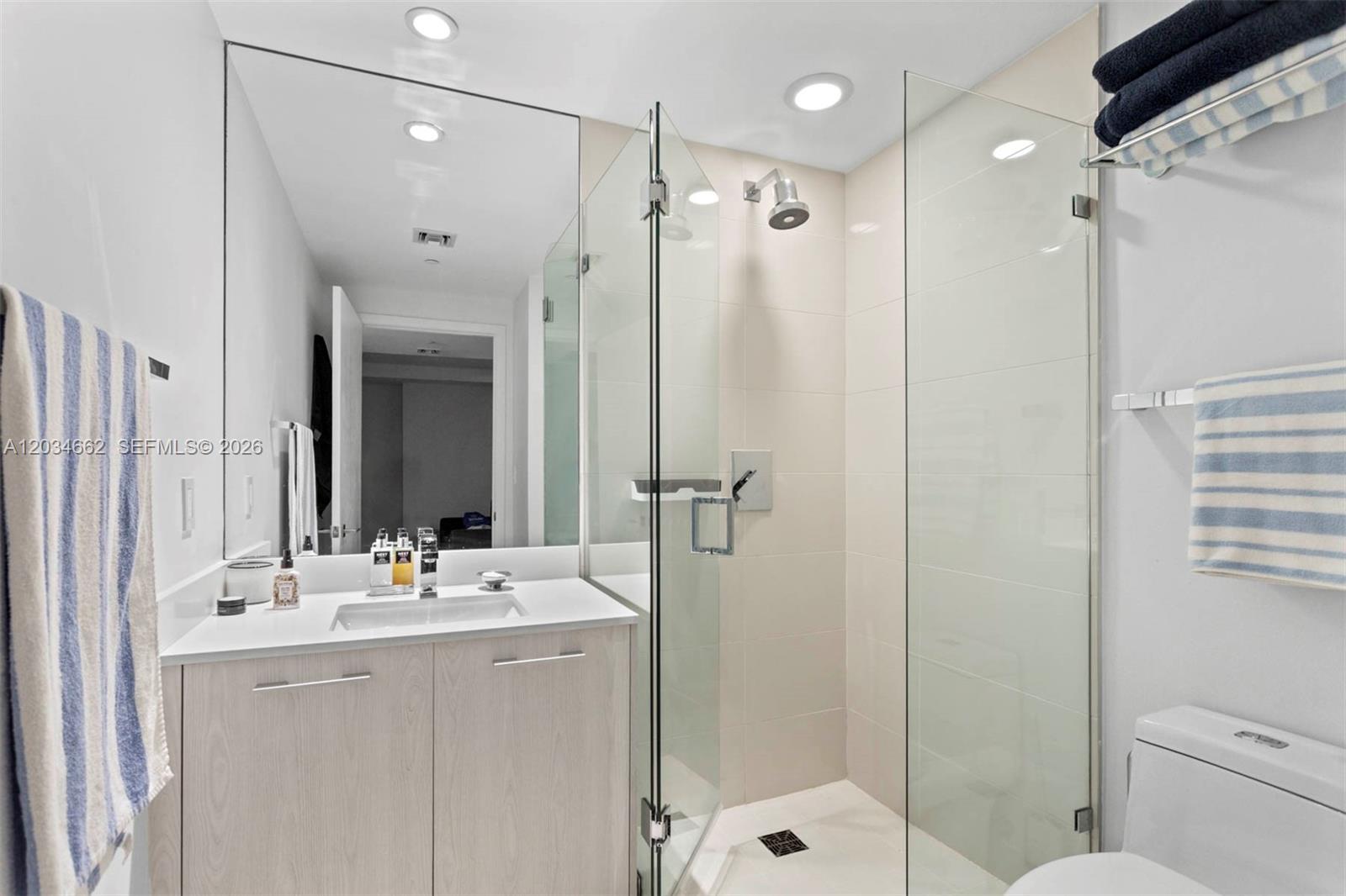A modern bathroom features a glass-enclosed shower, a vanity with a sink, and light-colored cabinetry — 55 SW 9th St # 1105, Miami FL 33130, MIAMI, FL