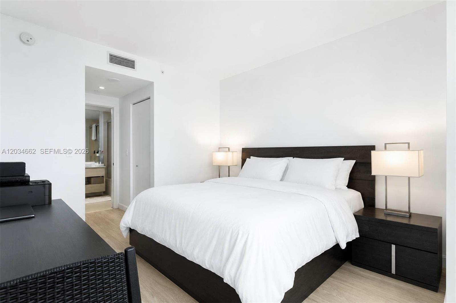A modern bedroom features a dark wood bed frame, matching nightstands, and an attached bathroom — 55 SW 9th St # 1105, Miami FL 33130, MIAMI, FL