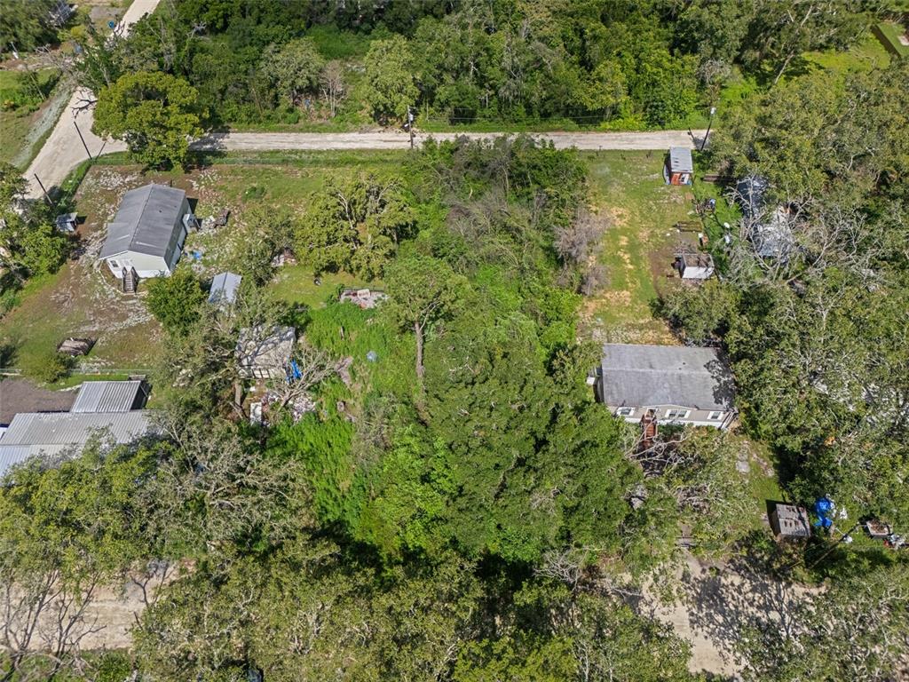 An aerial view shows two houses on a wooded lot with a dirt road nearby — 3241 TAFFETA STREET, DADE CITY, FL