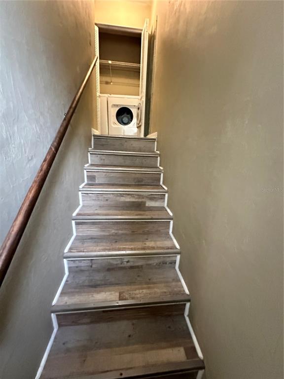 A staircase with wood-look vinyl treads leads up to a small laundry closet — 2735 SW 35TH PLACE UNIT 2001, GAINESVILLE, FL