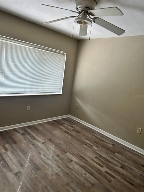 An empty bedroom features light-colored walls, a ceiling fan, and wood-look laminate flooring — 2735 SW 35TH PLACE UNIT 2001, GAINESVILLE, FL