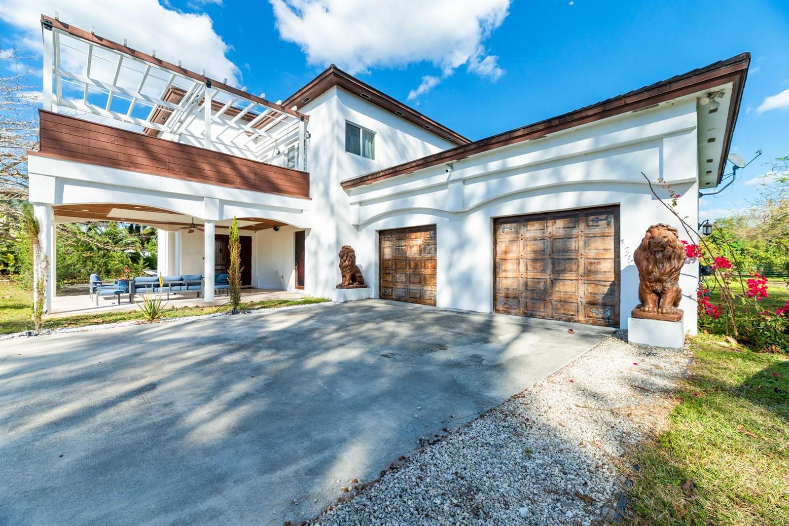 A white two-story house features a concrete driveway, two wooden garage doors, and lion statues — 4501 SW 143rd Avenue, Miramar FL 33027, MIRAMAR, FL