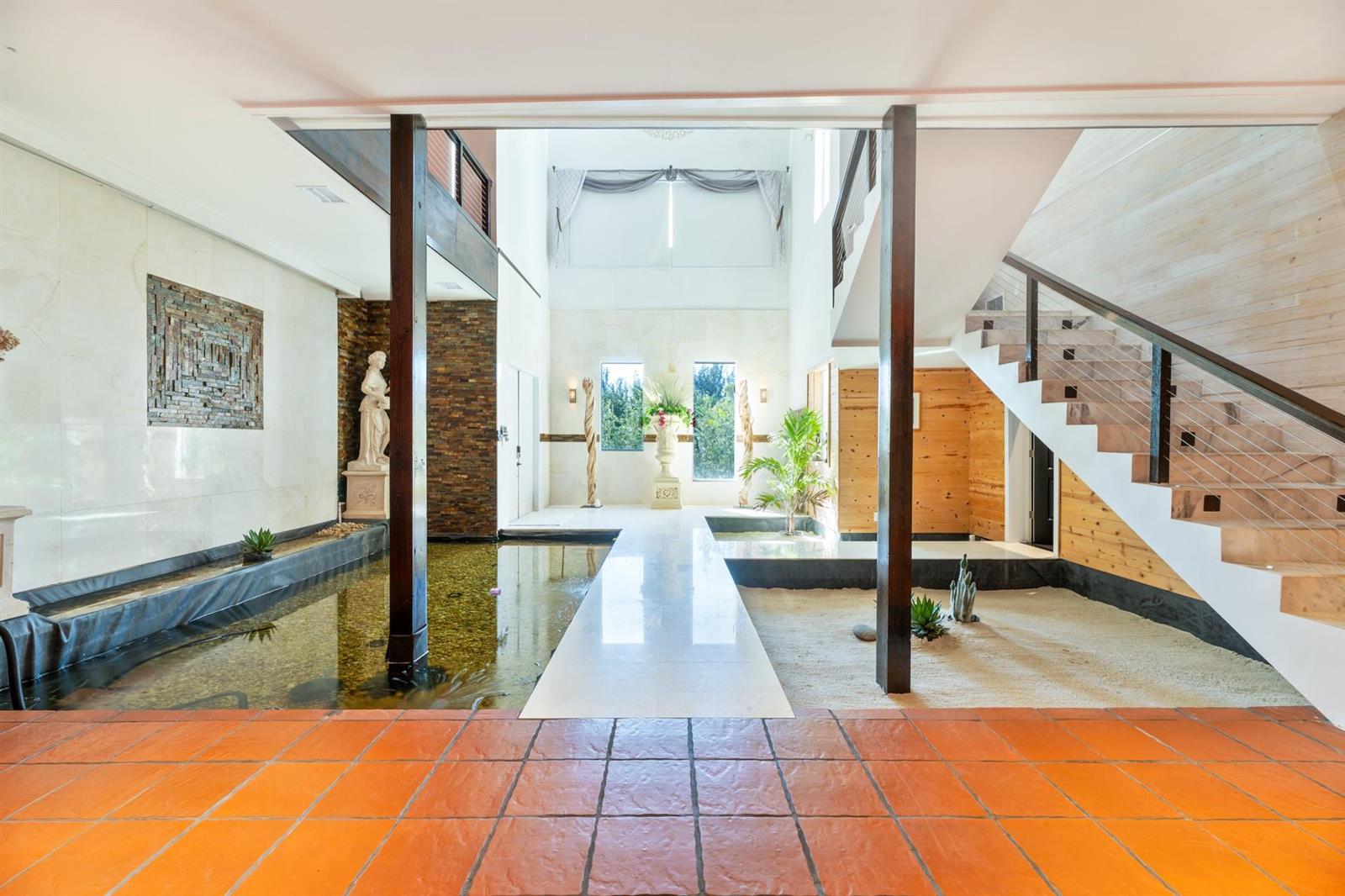 A grand foyer features a central walkway between an indoor koi pond and a rock garden — 4501 SW 143rd Avenue, Miramar FL 33027, MIRAMAR, FL