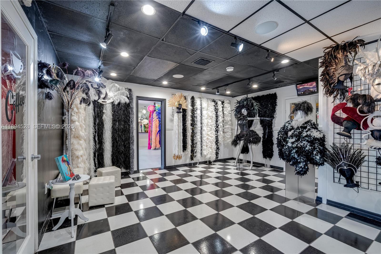 A retail space features a black-and-white checkered floor, black ceiling, and displays of feathered costumes — 1121 NW 29th St, Miami FL 33127, MIAMI, FL