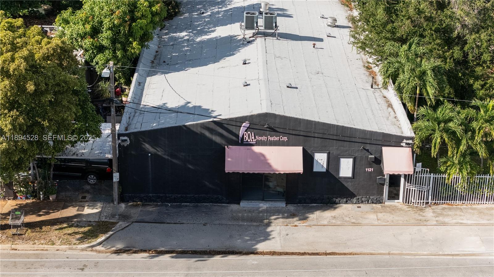 An aerial view shows a black commercial building with a metal roof and pink awnings — 1121 NW 29th St, Miami FL 33127, MIAMI, FL