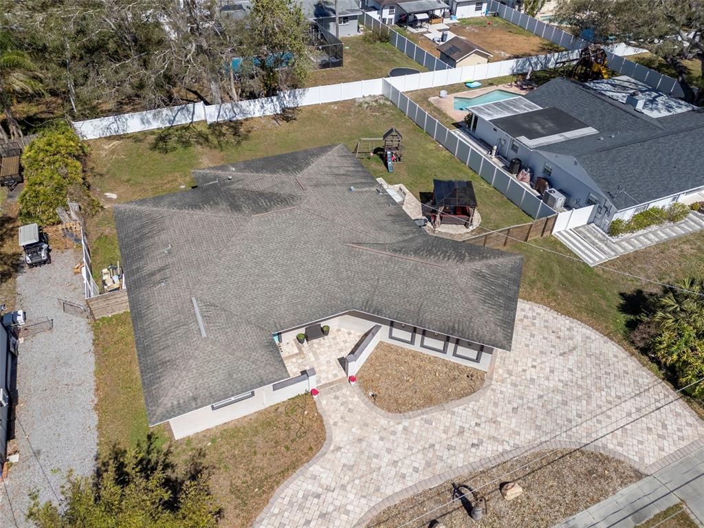 An aerial view shows a house with a shingled roof, paver driveway, and fenced backyard — 2535 LAKE ELLEN DRIVE, TAMPA, FL