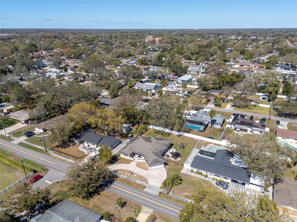 An aerial view shows a suburban neighborhood with houses, swimming pools, and tree-lined streets — 2535 LAKE ELLEN DRIVE, TAMPA, FL
