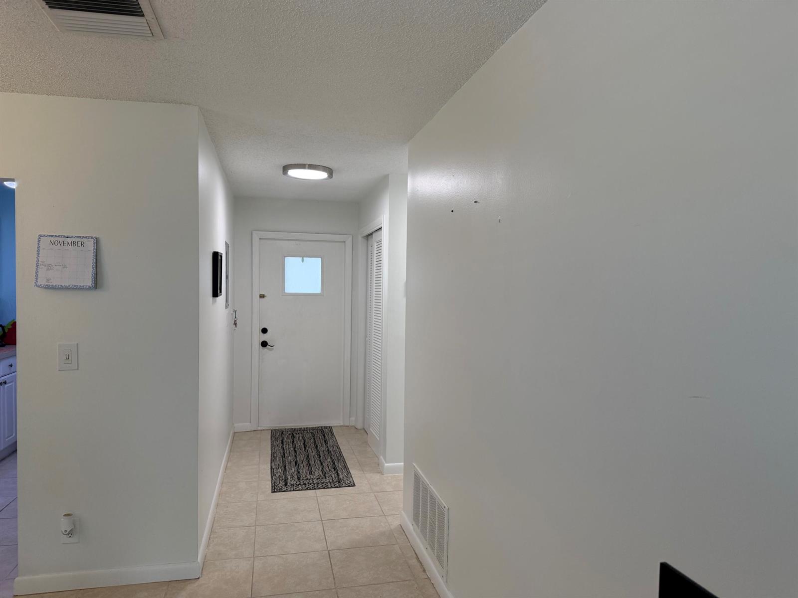 A hallway features white walls, tile flooring, a front door, and a ceiling light fixture — 300 SW Golfview Terrace # 152, Boynton Beach FL 33426, BOYNTON BEACH, FL