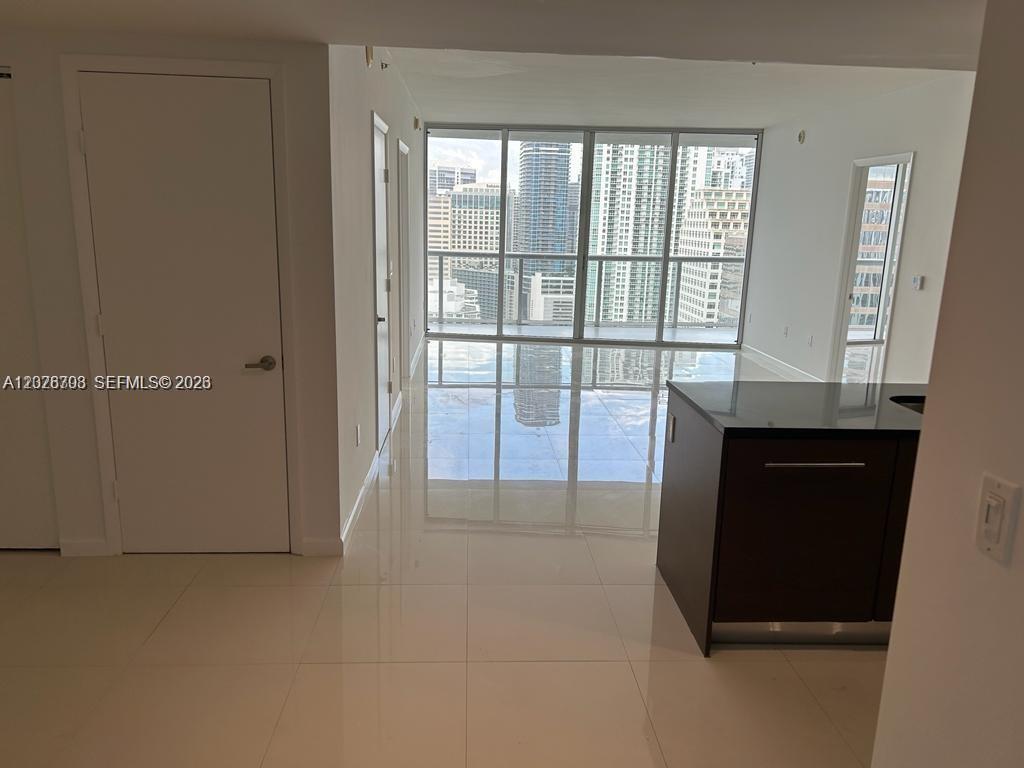 A modern room features white tile floors, a dark kitchen island, and floor-to-ceiling windows — 495 Brickell Ave # 3203, Miami FL 33131, MIAMI, FL