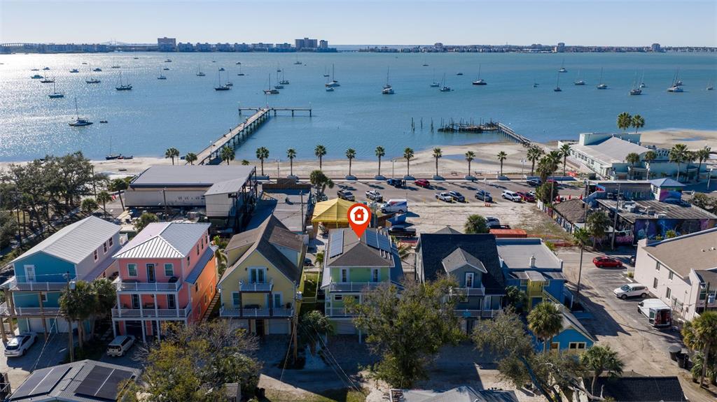A two-story light green house features a balcony, French doors, and a brick walkway — 5429 ESSEX AVENUE S, GULFPORT, FL