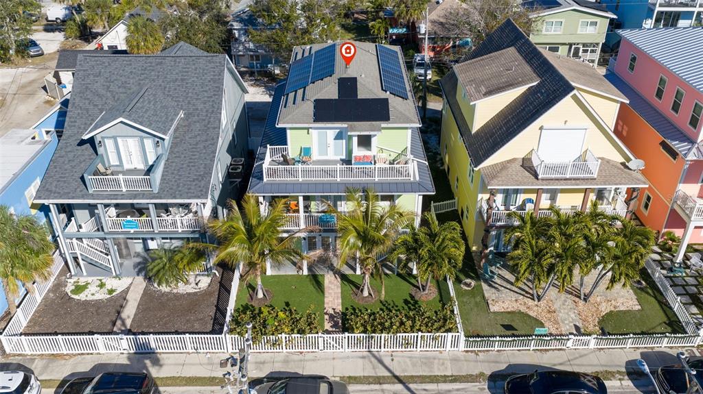 A covered wooden balcony features white railings, wicker furniture, and views of palm trees — 5429 ESSEX AVENUE S, GULFPORT, FL