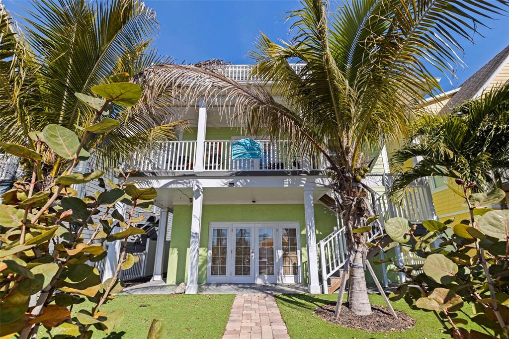 A light green house features a wooden deck with outdoor seating and white railings — 5429 ESSEX AVENUE S, GULFPORT, FL