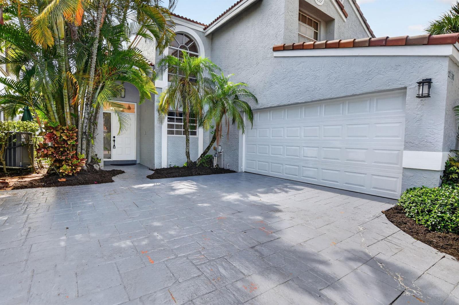 A two-story house with a gray stucco exterior, a white garage door, and a paved driveway — 23338 La Vida Way, Boca Raton FL 33433, BOCA RATON, FL