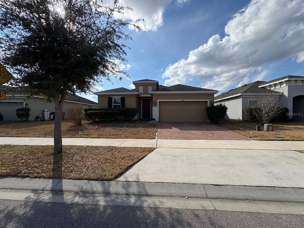 A single-story suburban house with a tan exterior, a two-car garage, and a paved driveway — 4813 MARCOS CIRCLE, KISSIMMEE, FL