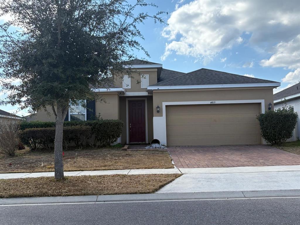 A single-story house with a tan stucco exterior, a two-car garage, and a front door — 4813 MARCOS CIRCLE, KISSIMMEE, FL