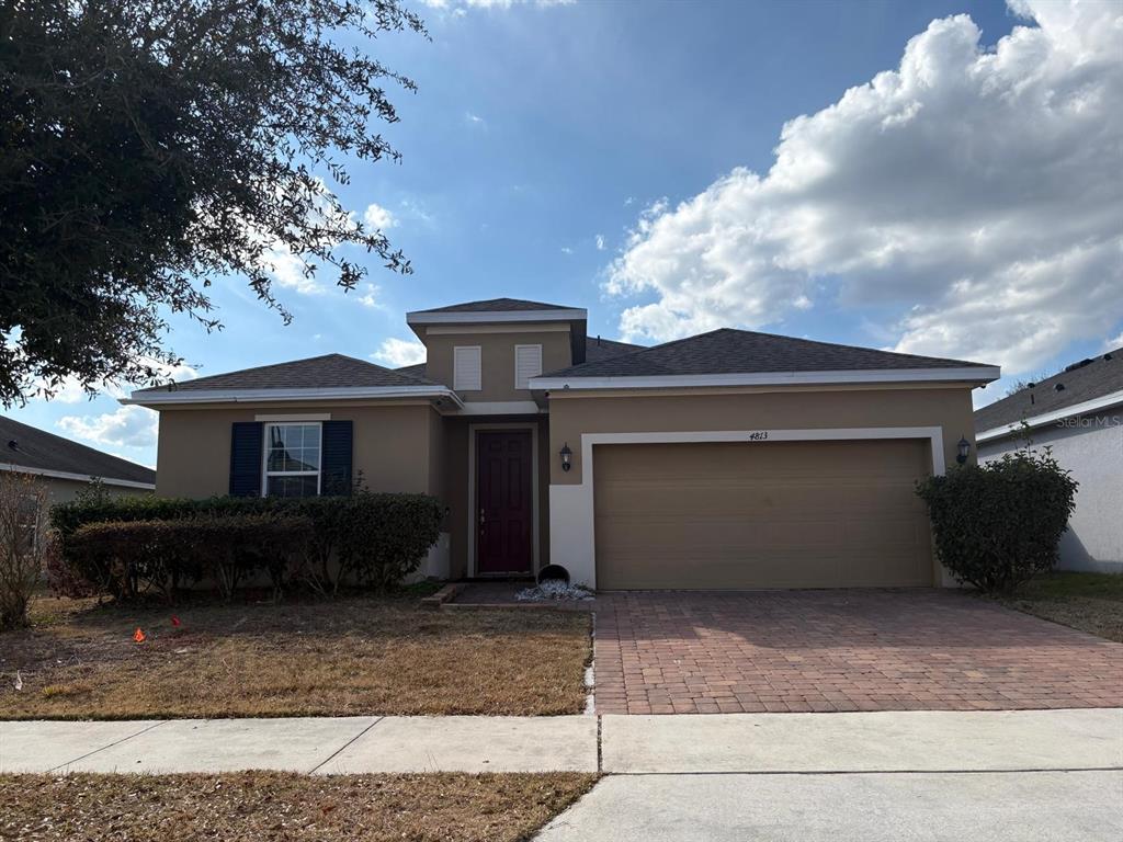 A single-story house with a tan stucco exterior, a two-car garage, and a brick driveway — 4813 MARCOS CIRCLE, KISSIMMEE, FL