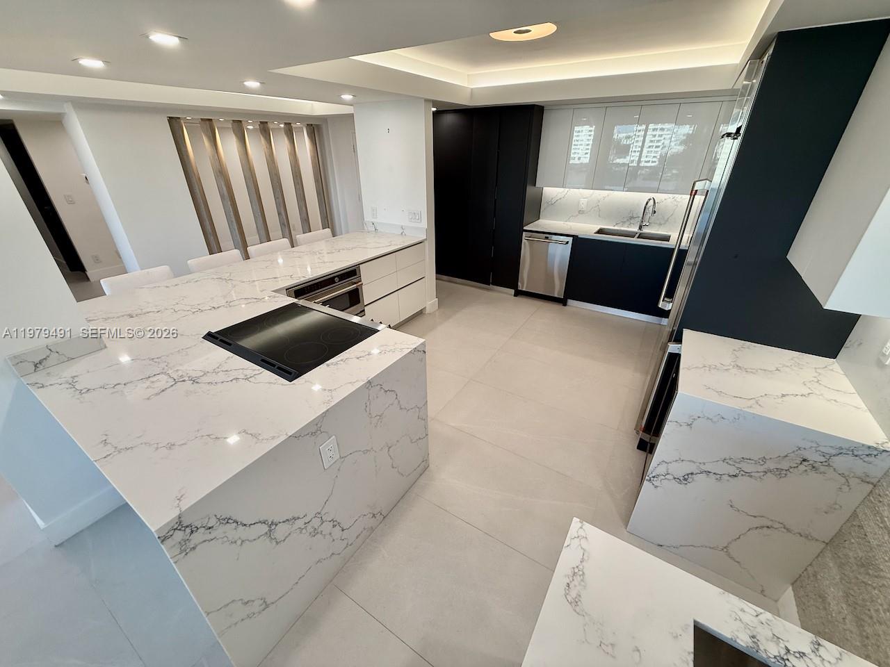 A modern kitchen features a marble-topped island, stainless steel appliances, and high-contrast cabinetry — 900 Bay Dr # 524, Miami Beach FL 33141, MIAMI BEACH, FL